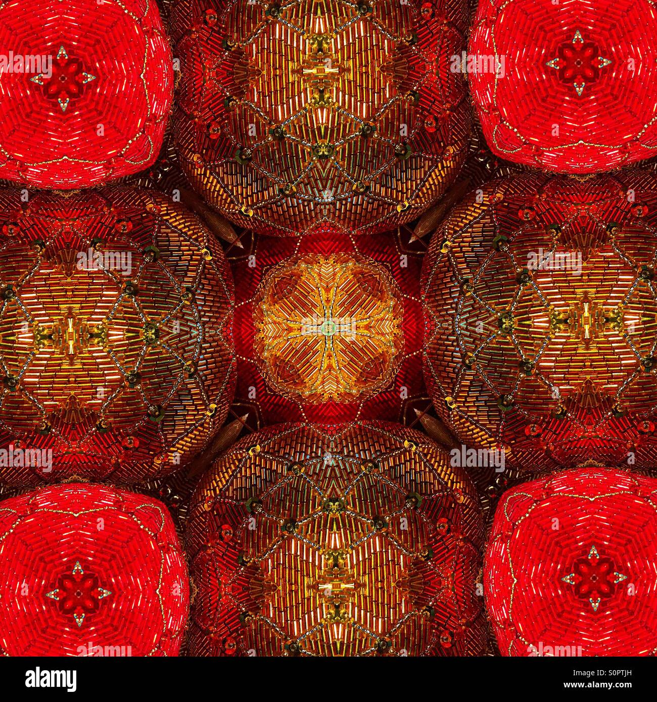 A macro view of a kaleidoscopic image of sequined balls in red and gold, with a star or cross shape in the center. - Smartphone Captured Stock Image