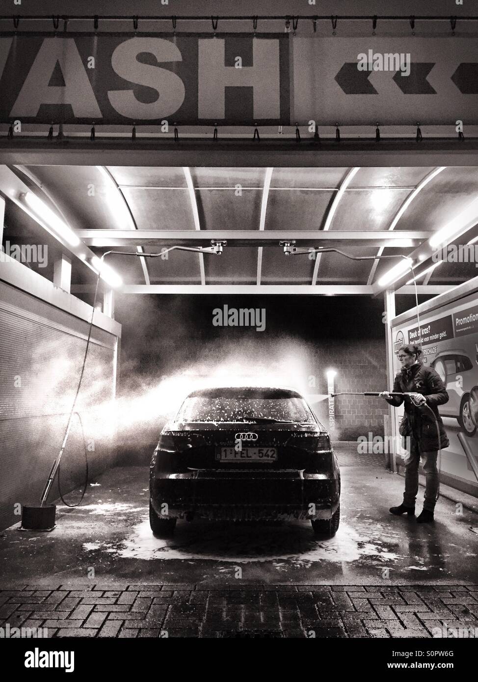 Woman cleaning her car in a self service car wash - Smartphone Captured Stock Image