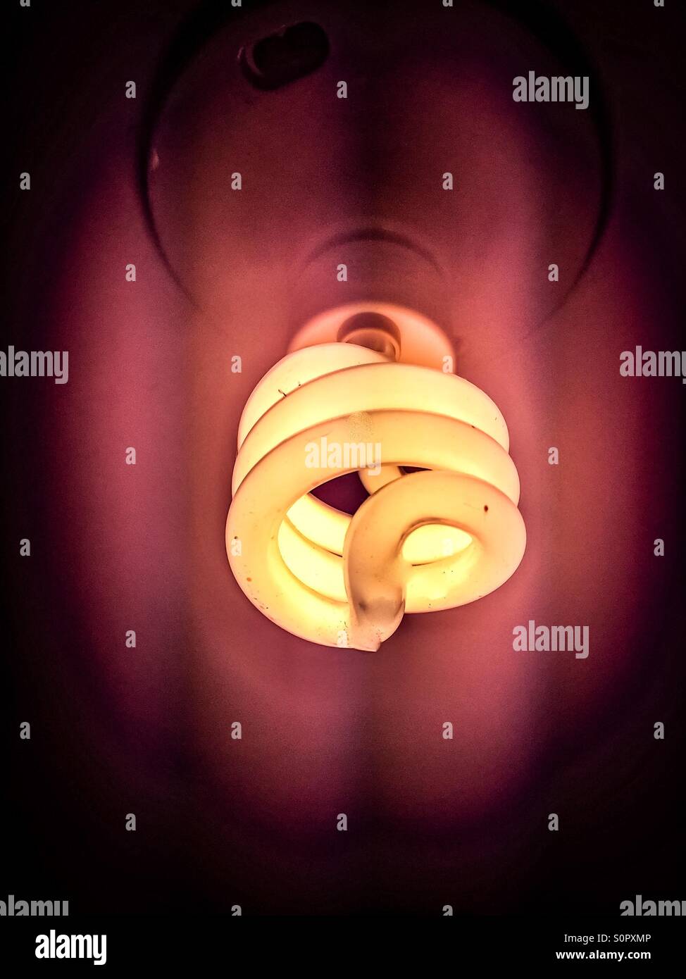Coiled bulb. A compact fluorescent bulb in ON position. Economical. Less than 10 percent of the power consumption of a comparable incandescent bulb. Long life. - Smartphone Captured Stock Image