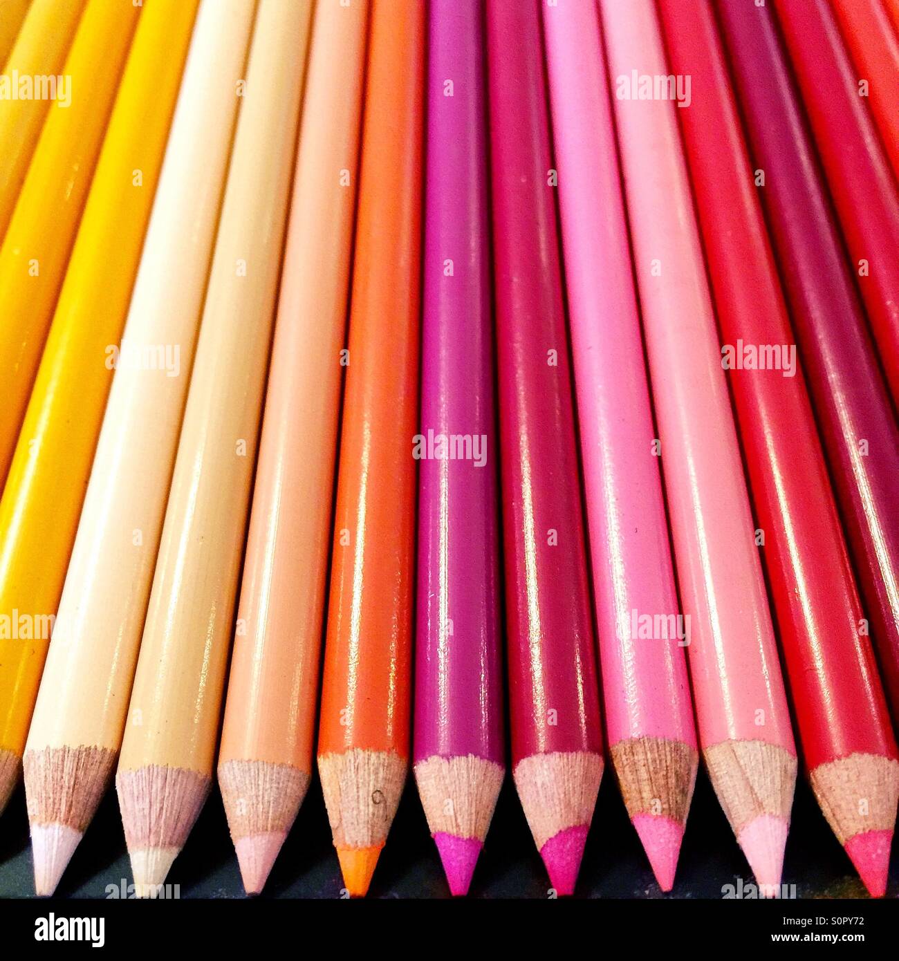 Red, pink and yellow colored pencils aligned in a row. - Smartphone Captured Stock Image