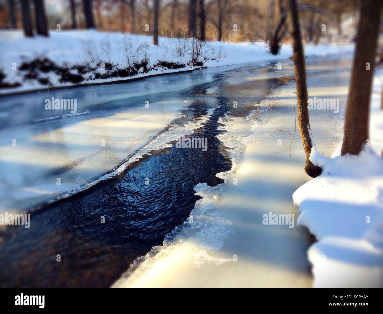 An opening in an otherwise frozen creek. Stock Photo