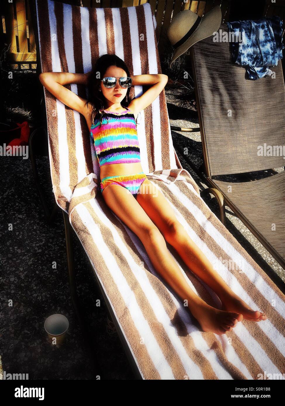 Girl relaxing on lounge chair in sun - Smartphone Captured Stock Image