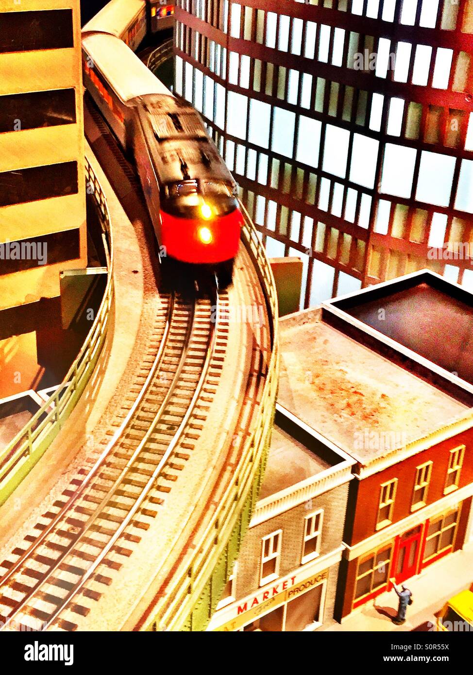 A miniature locomotive runs on the tracks in an urban railway modelling layout. - Smartphone Captured Stock Image