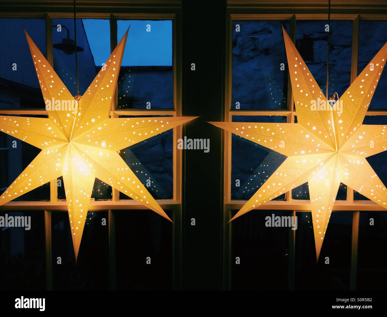 Two festive star lanterns illuminated in a window. - Smartphone Captured Stock Image