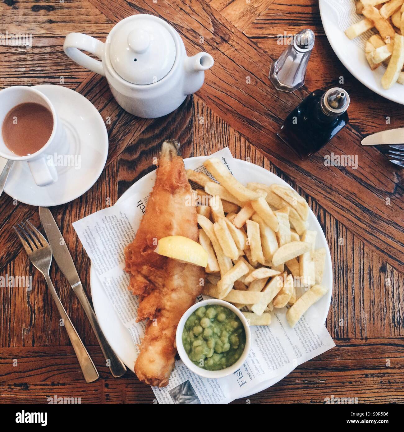 A plate of fish and chips, with mushy peas and a cup of tea. Seahouses, UK. - Smartphone Captured Stock Image