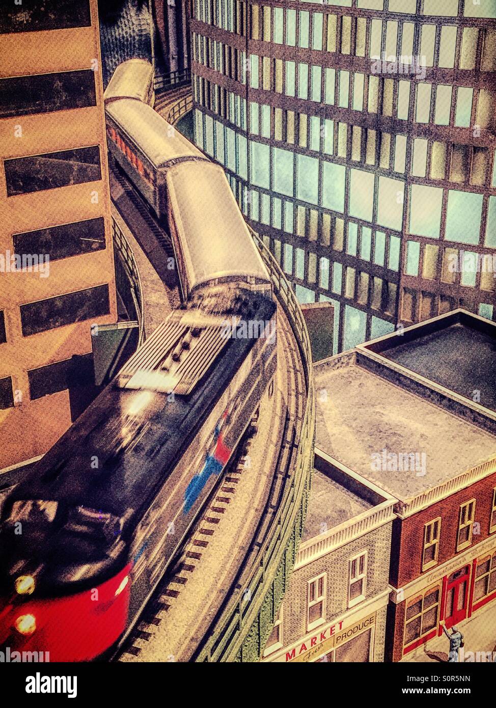 A miniature locomotive runs on the tracks of an urban railway modeling layout. - Smartphone Captured Stock Image