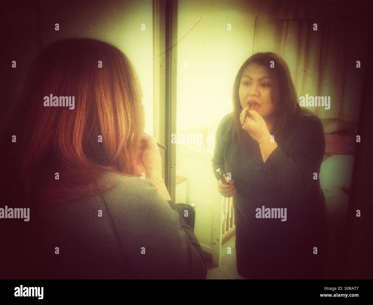 A lady uses a mirrored wardrobe door to do her makeup. - Smartphone Captured Stock Image