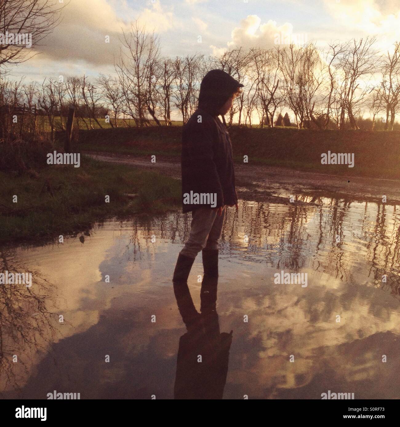Boy standing in a large puddle, Hampshire, England. - Smartphone Captured Stock Image