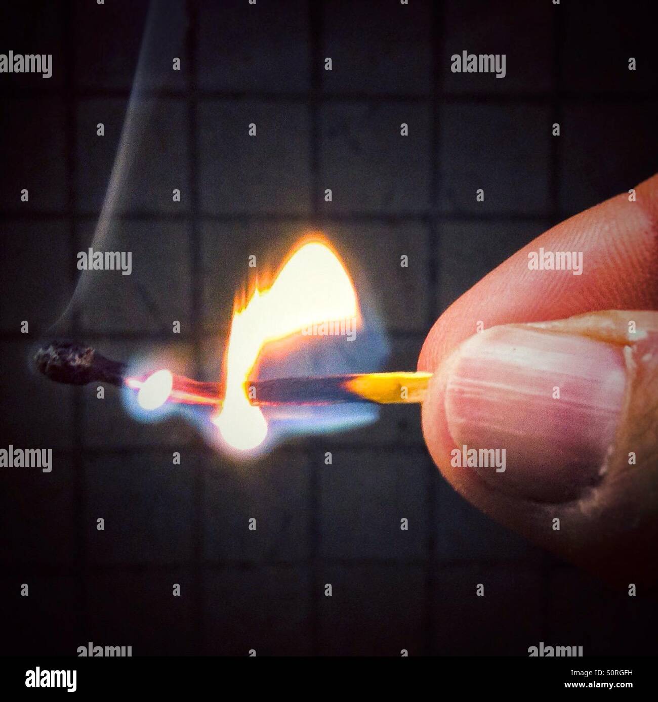 Hand holding burning match stick - Smartphone Captured Stock Image
