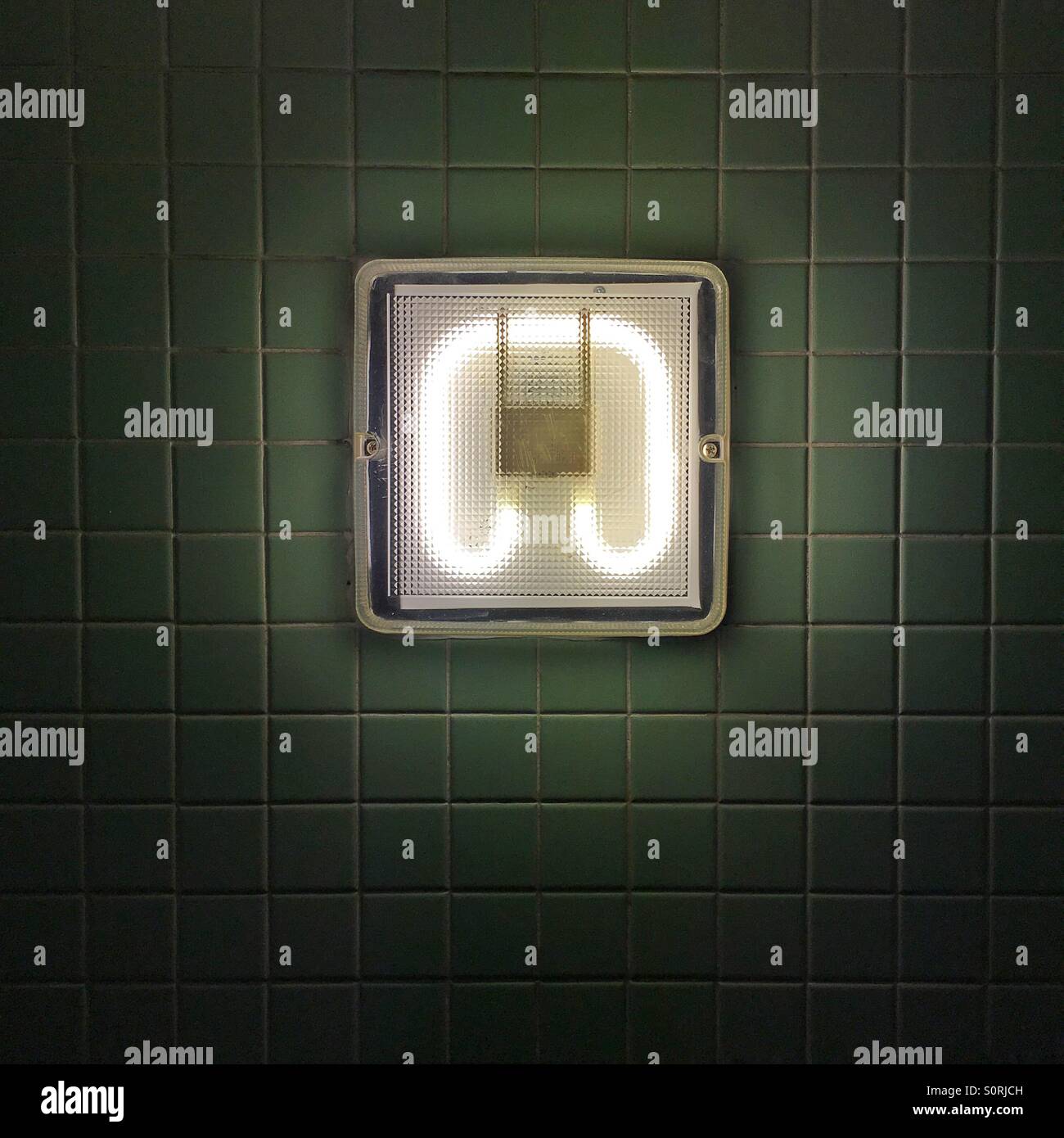 Light in Bathroom against white tile.  Influenced by William Eggleston Stock Photo