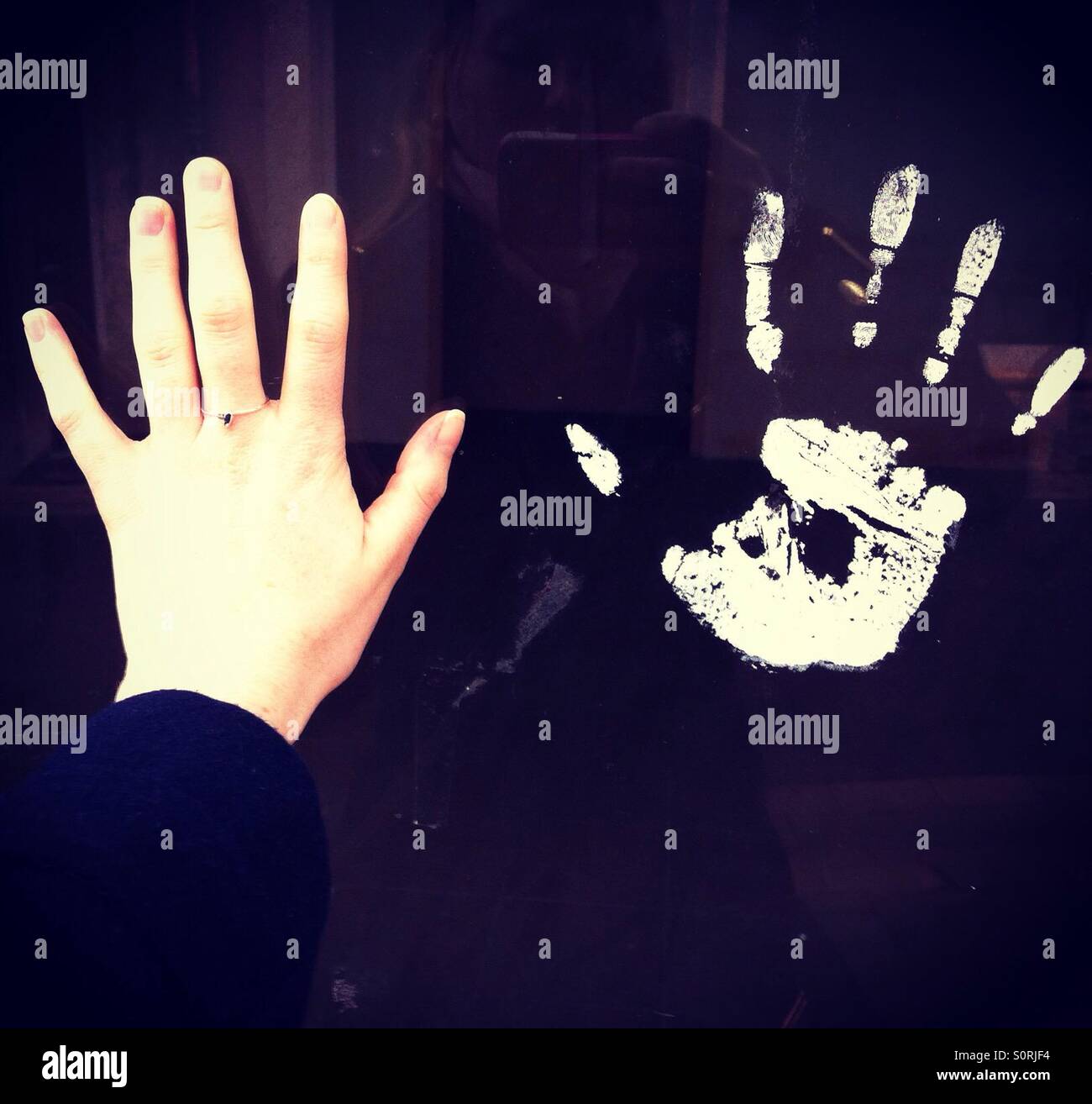 Hand next to hand print on a window Stock Photo - Alamy
