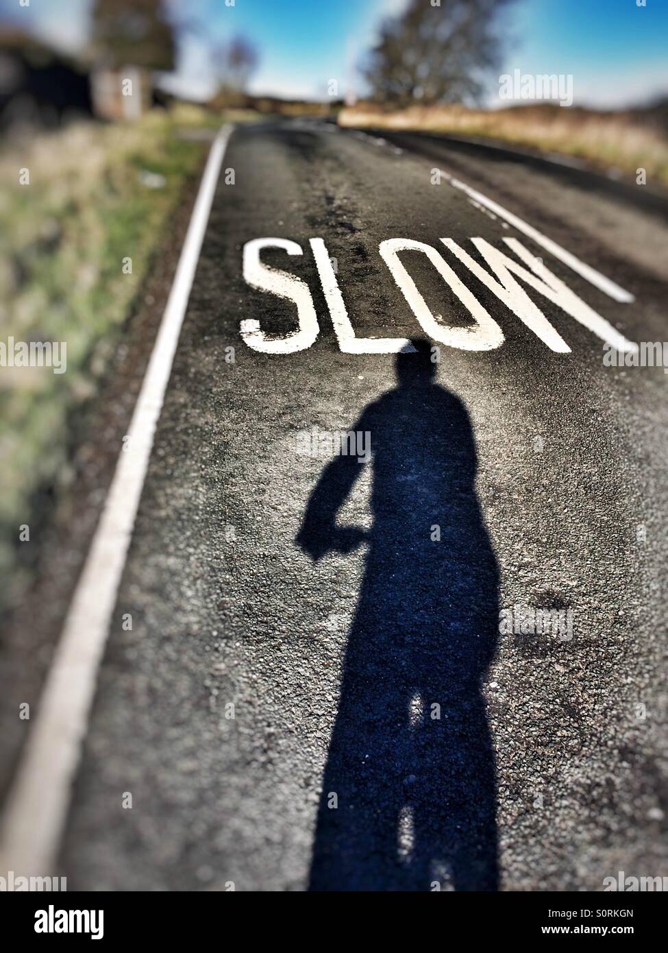 Cyclist shadow Selfie approaching a slow sign on the road - Smartphone Captured Stock Image
