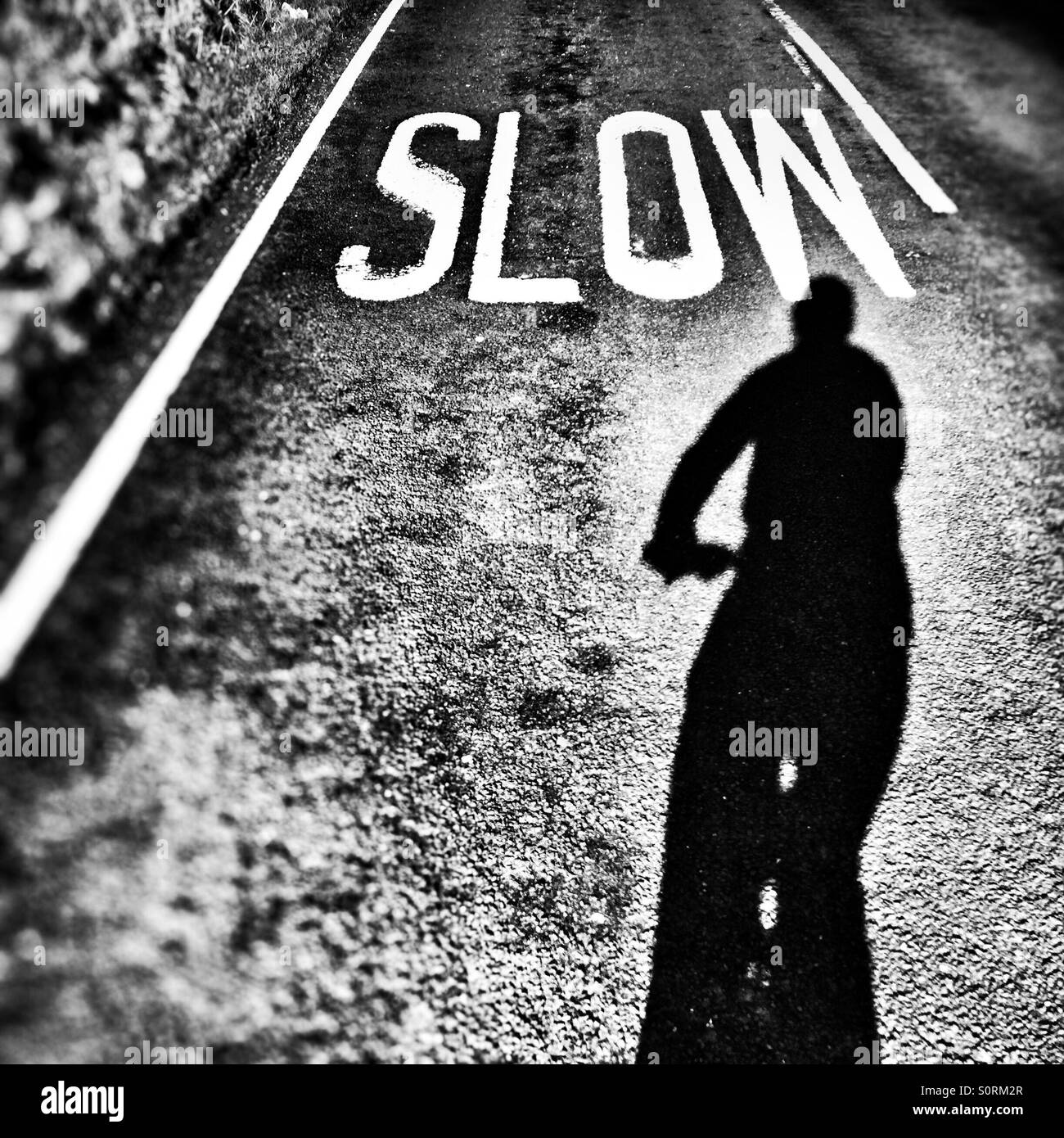Slow sign on the road in front of cyclists shadow Selfie Stock Photo