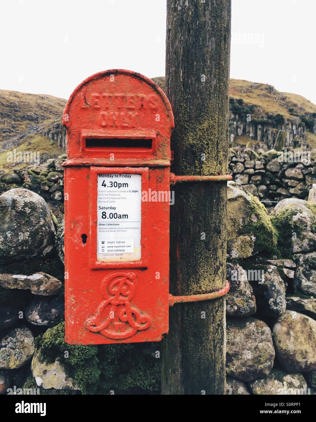 A small traditional red Royal Mail letter box in rural Teesdale, UK. Stock Photo