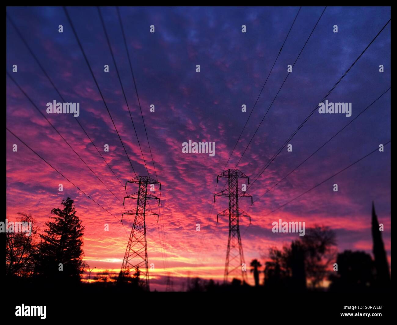 Power lines and pylons with a dramatic sunset sky. Modesto, Stanislaus County, California, USA - Smartphone Captured Stock Image