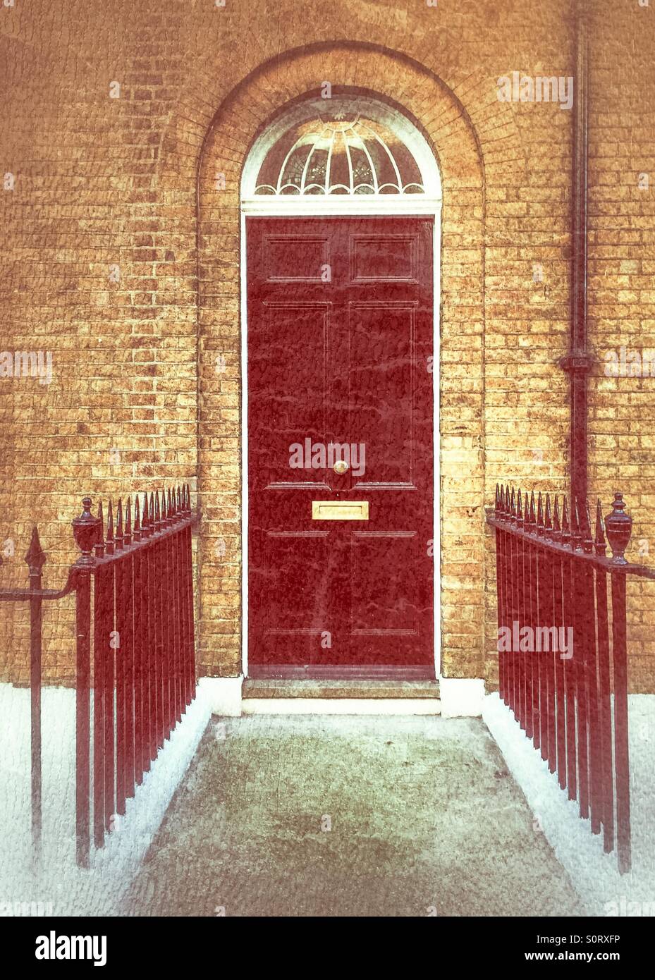 Black front door with iron railings in a brick building - Smartphone Captured Stock Image