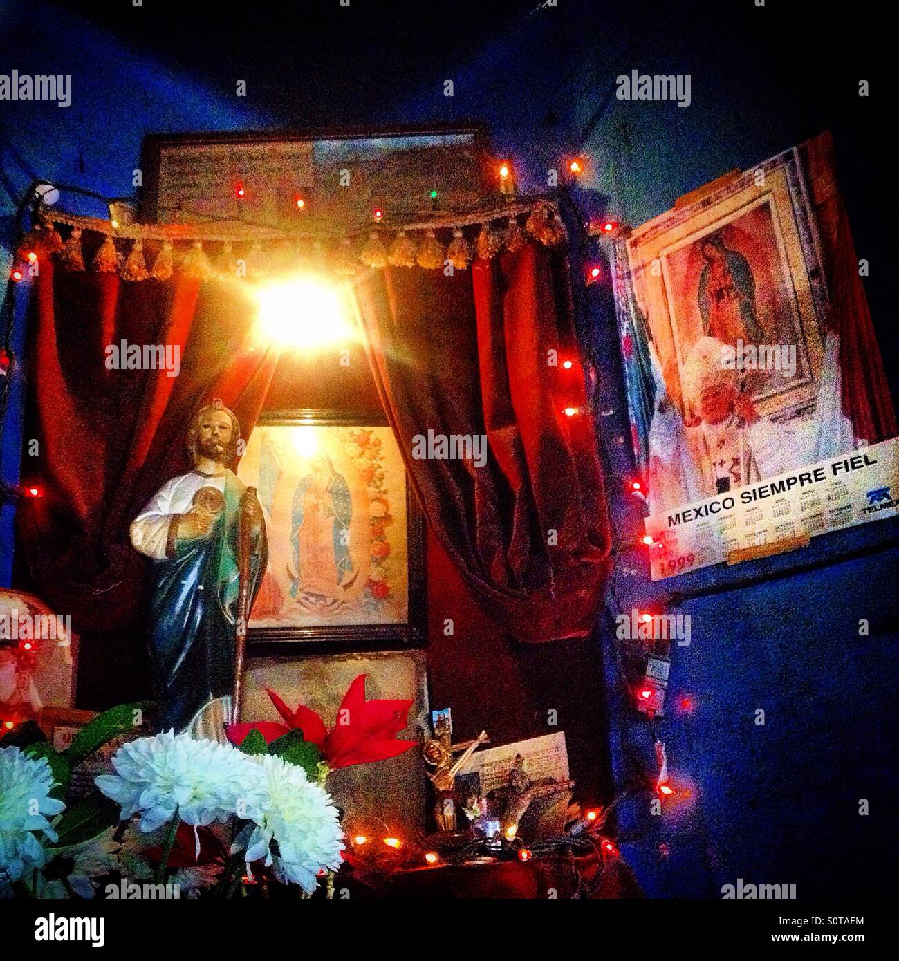 An altar with images of Sain Jude Thaddeus and Our Lady of Guadalupe decorated with electric lights and roses in Colonia Roma, Mexico City, Mexico Stock Photo
