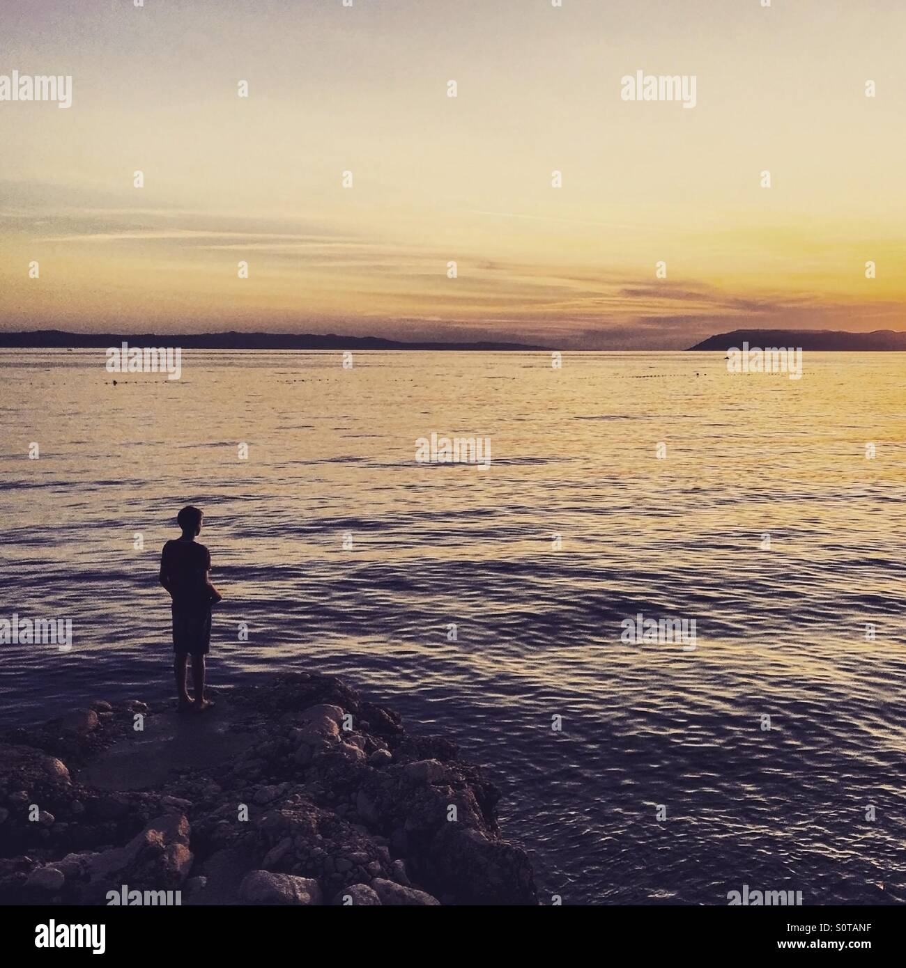 Man standing on sea coast and watching sunset Stock Photo