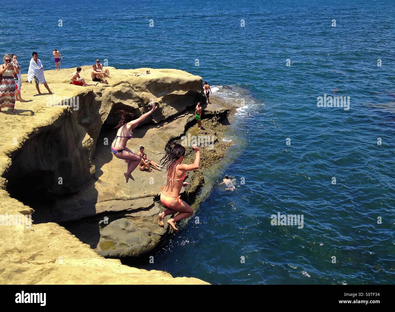 Two women jumping off cliff into ocean, summer fun lifestyle, Sunset Cliffs,  Point Loma, California Stock Photo - Alamy