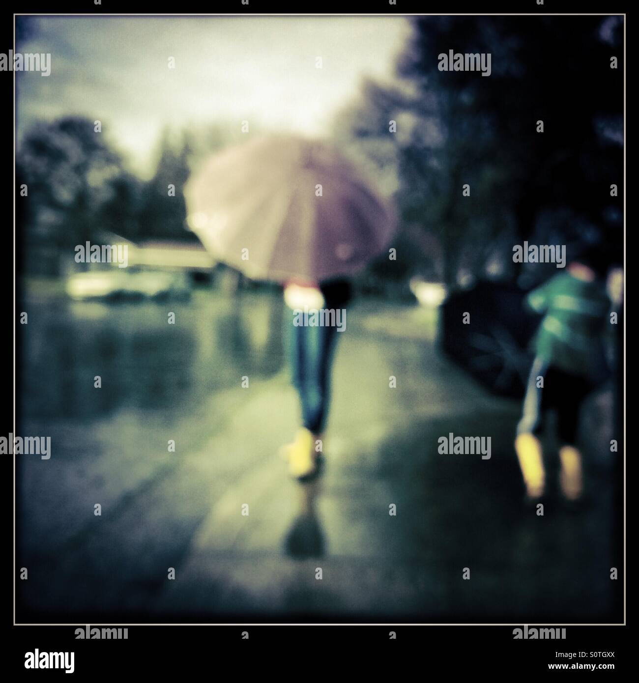 A 12 year old girl and her 7 year old brother play outside in the rain. - Smartphone Captured Stock Image