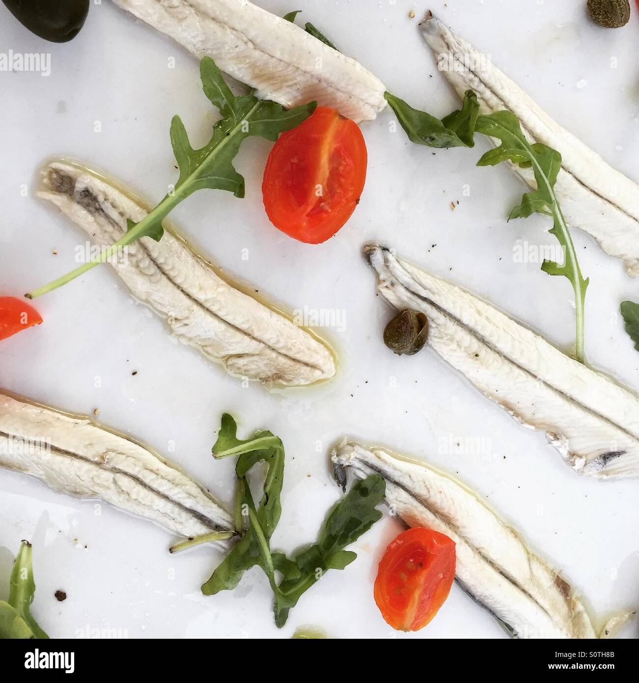 Marinated anchovies fish with tomatoes and capers on plate Stock Photo