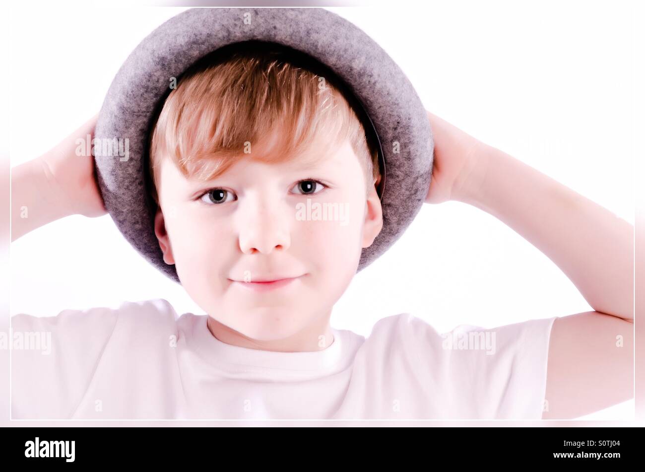 Young boy holding onto his hat. Stock Photo