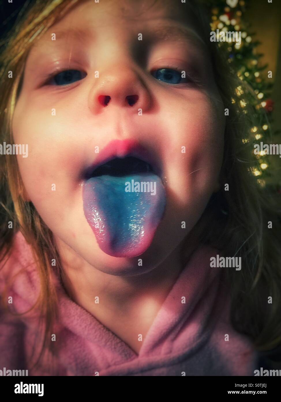 Little girl sticking out her blue tongue Stock Photo