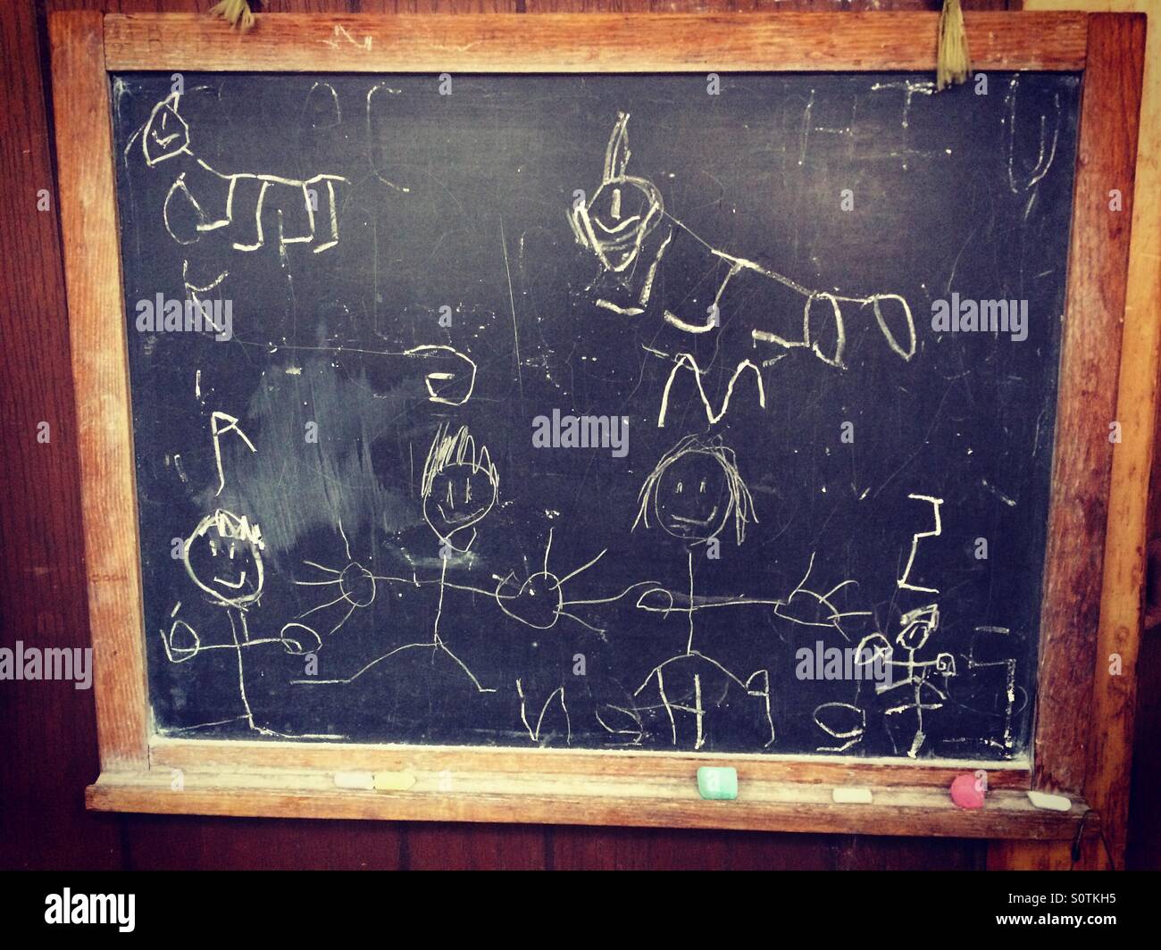 A 5 year old boy's chalkboard drawing of his family, complete with the dog and cat. - Smartphone Captured Stock Image