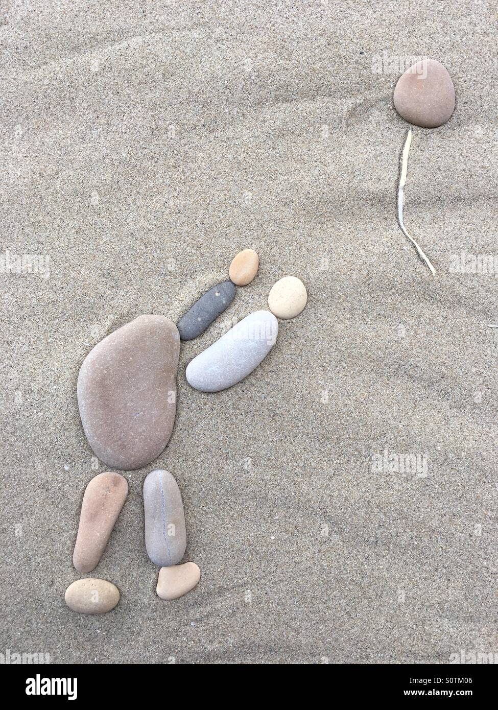 Person loosing his head, conceptual composition with pebbles and stones over beach sand - Smartphone Captured Stock Image