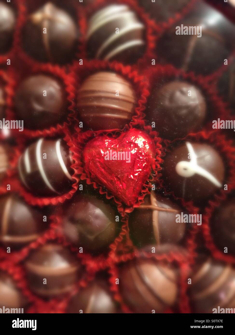 Box of Saint Valentine's Day chocolates with heart shaped for oil wrapped heart in center. - Smartphone Captured Stock Image