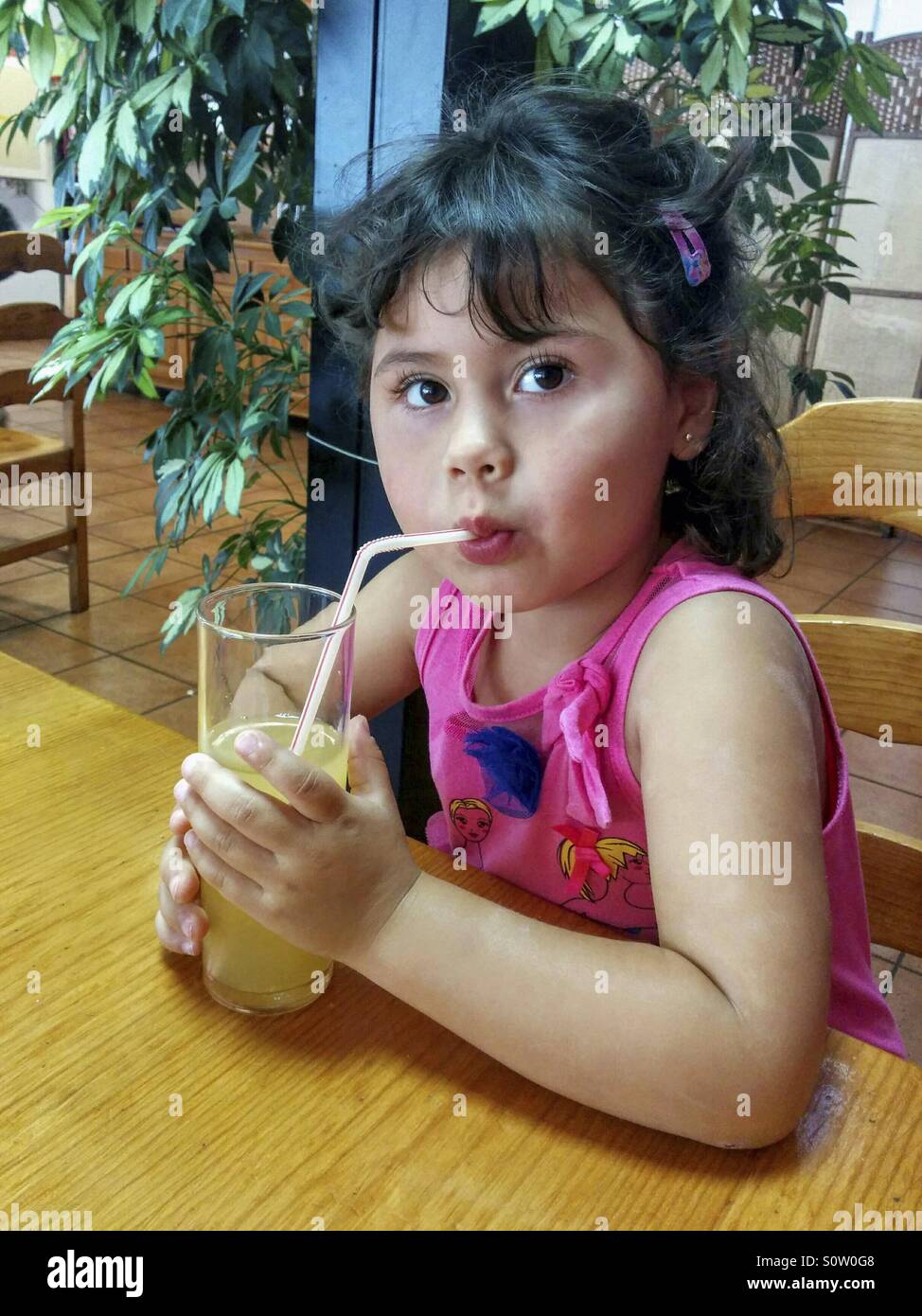 Little girl drinking an orange juice Stock Photo - Alamy