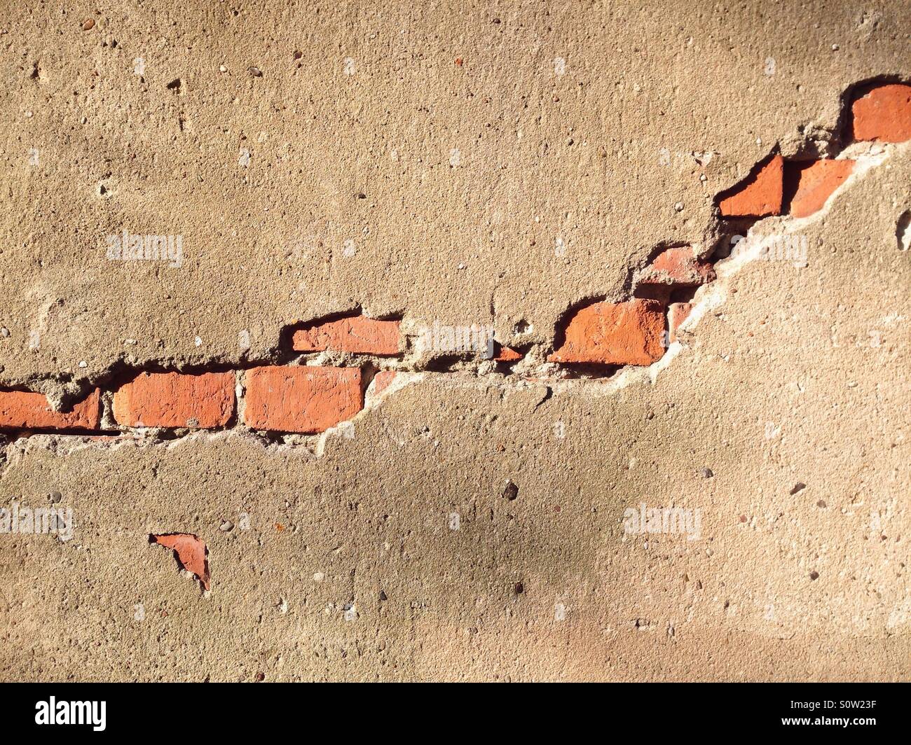 Bricks showing through the plaster on a wall creating a rift effect - Smartphone Captured Stock Image