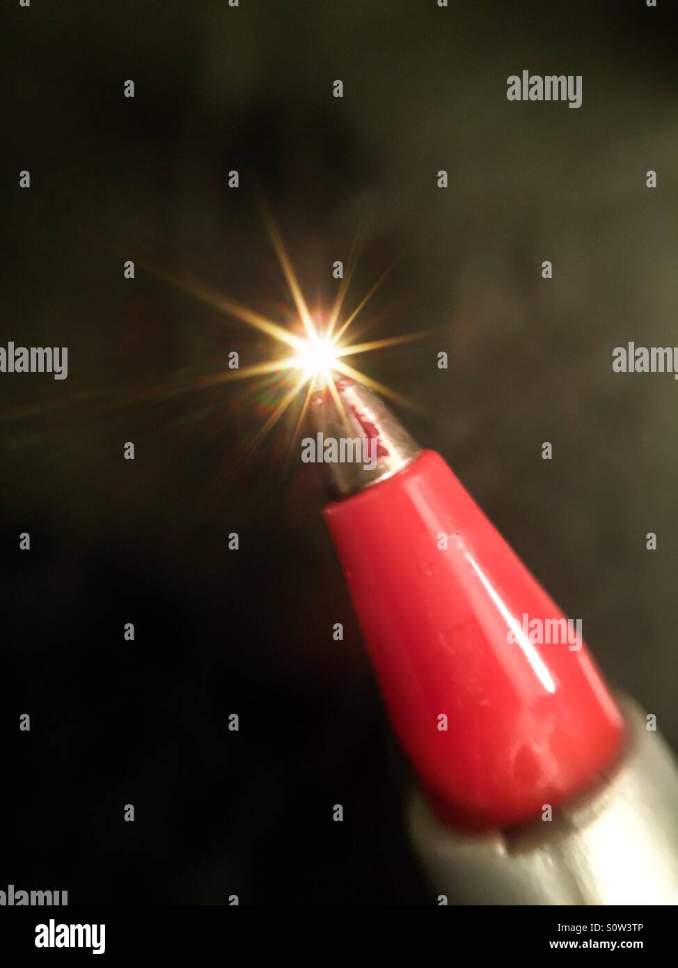 Live point. A spark at the end of a metal instrument. Concepts: point of light, darkness surrounds, breakthrough, single, classic style. Synaptic, synapsis firing. - Smartphone Captured Stock Image