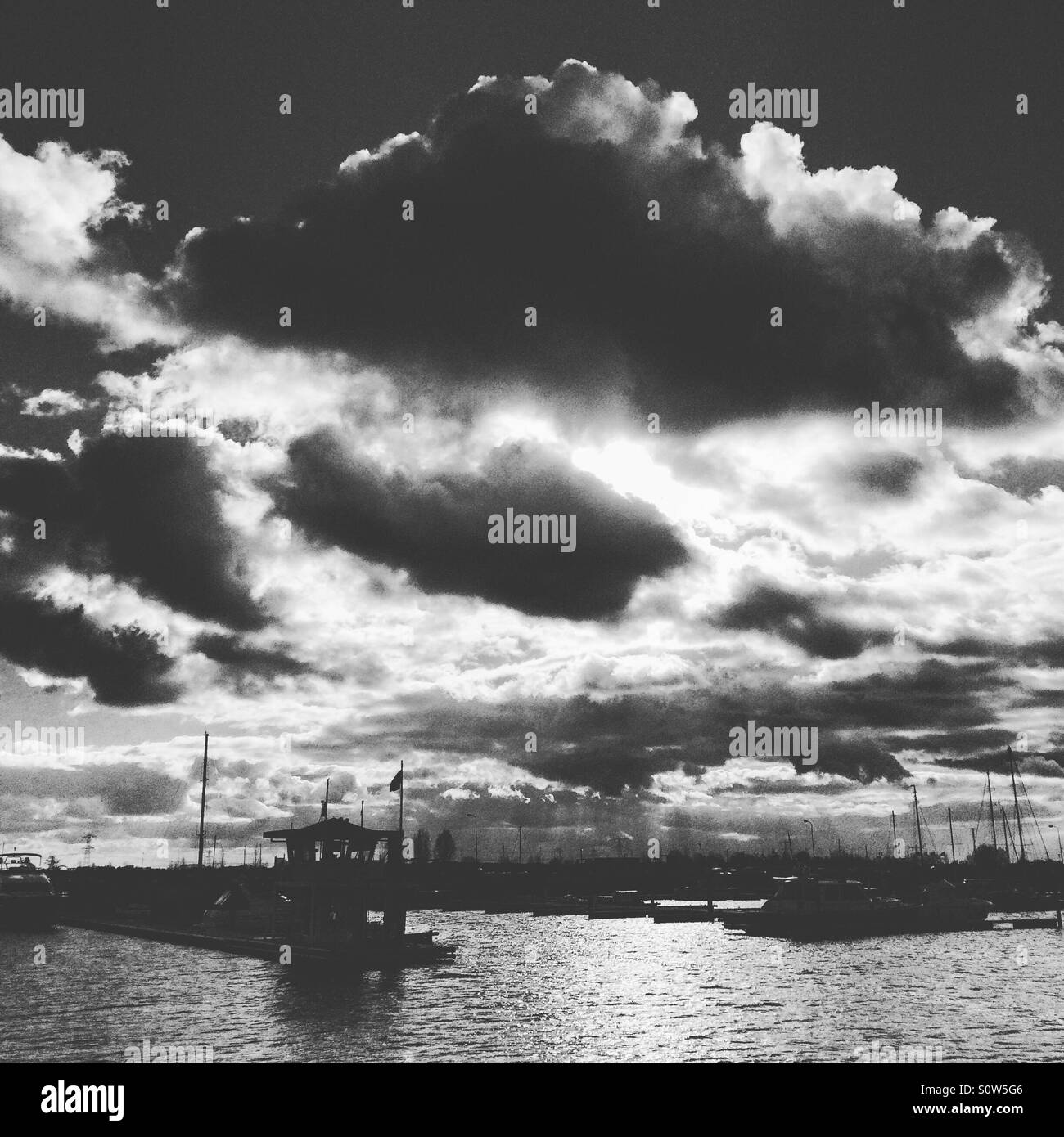 Waiting for the sun. View of a yacht harbor with sun behind clouds. - Smartphone Captured Stock Image