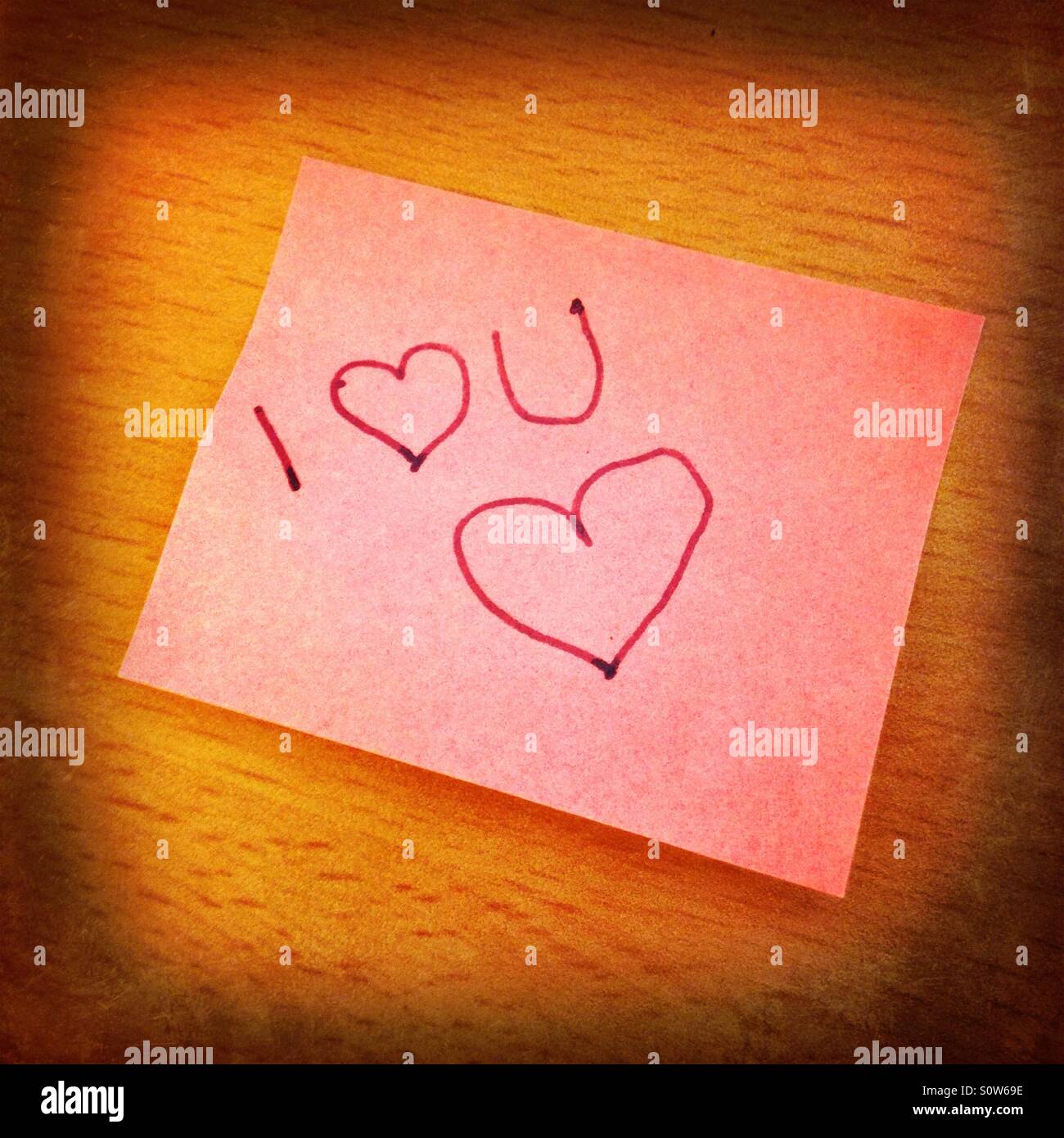A pink I love you sticky note on a wooden table Stock Photo