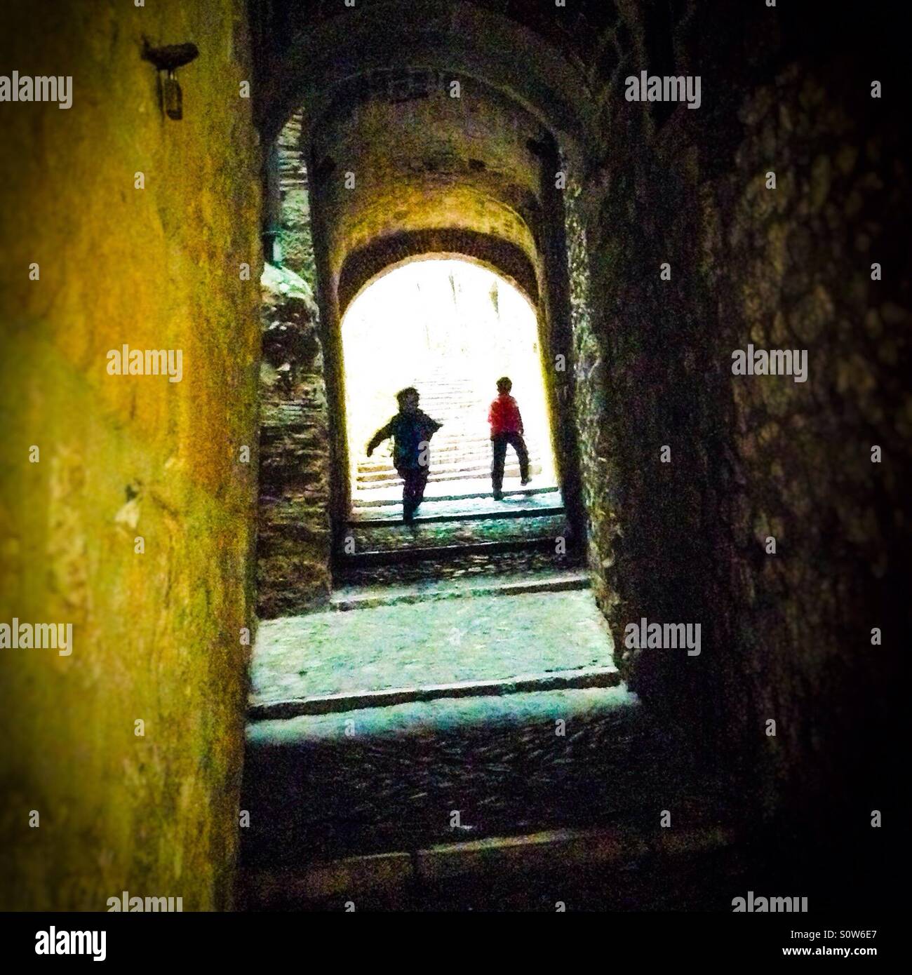 Two silhouettes walking through a dark alley in the Call (jewish quarter), Girona, Catalonia - Smartphone Captured Stock Image