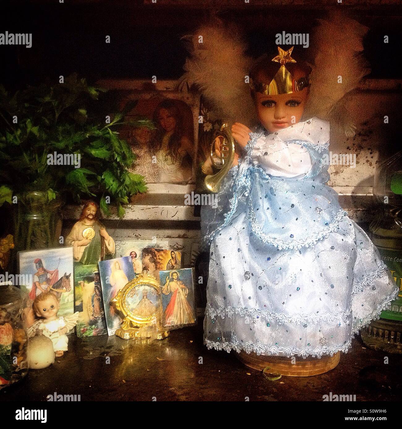 A Baby Jesus sculpture decorates an altar with saints in Mercado de Medellin, Colonia Roma, Mexico City, Mexico - Smartphone Captured Stock Image