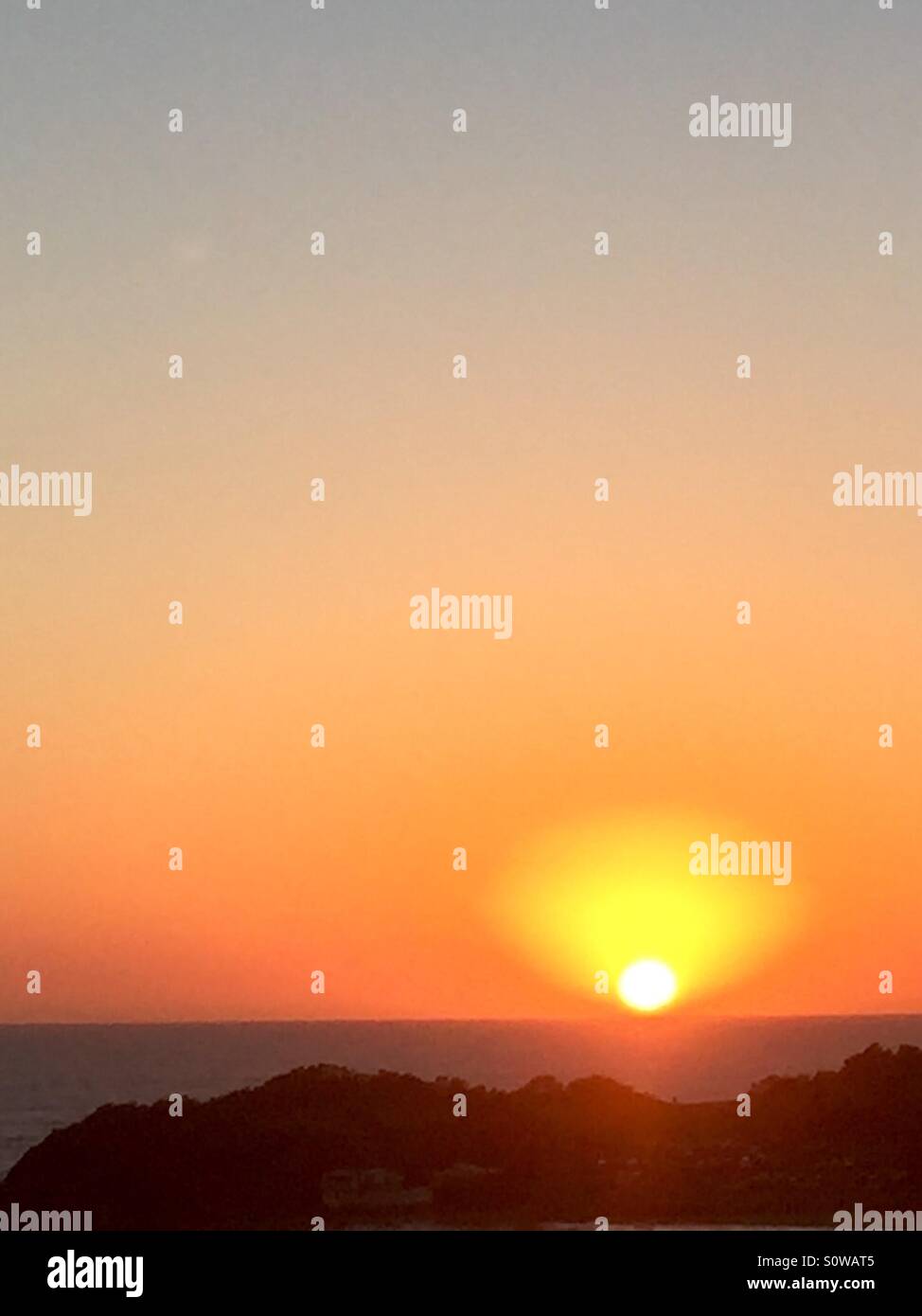 Sunrise Australia 5.20am in February  2016. Golden heavenly sky above the landscape with orange and red sun rise  light above a dark sea.. - Smartphone Captured Stock Image