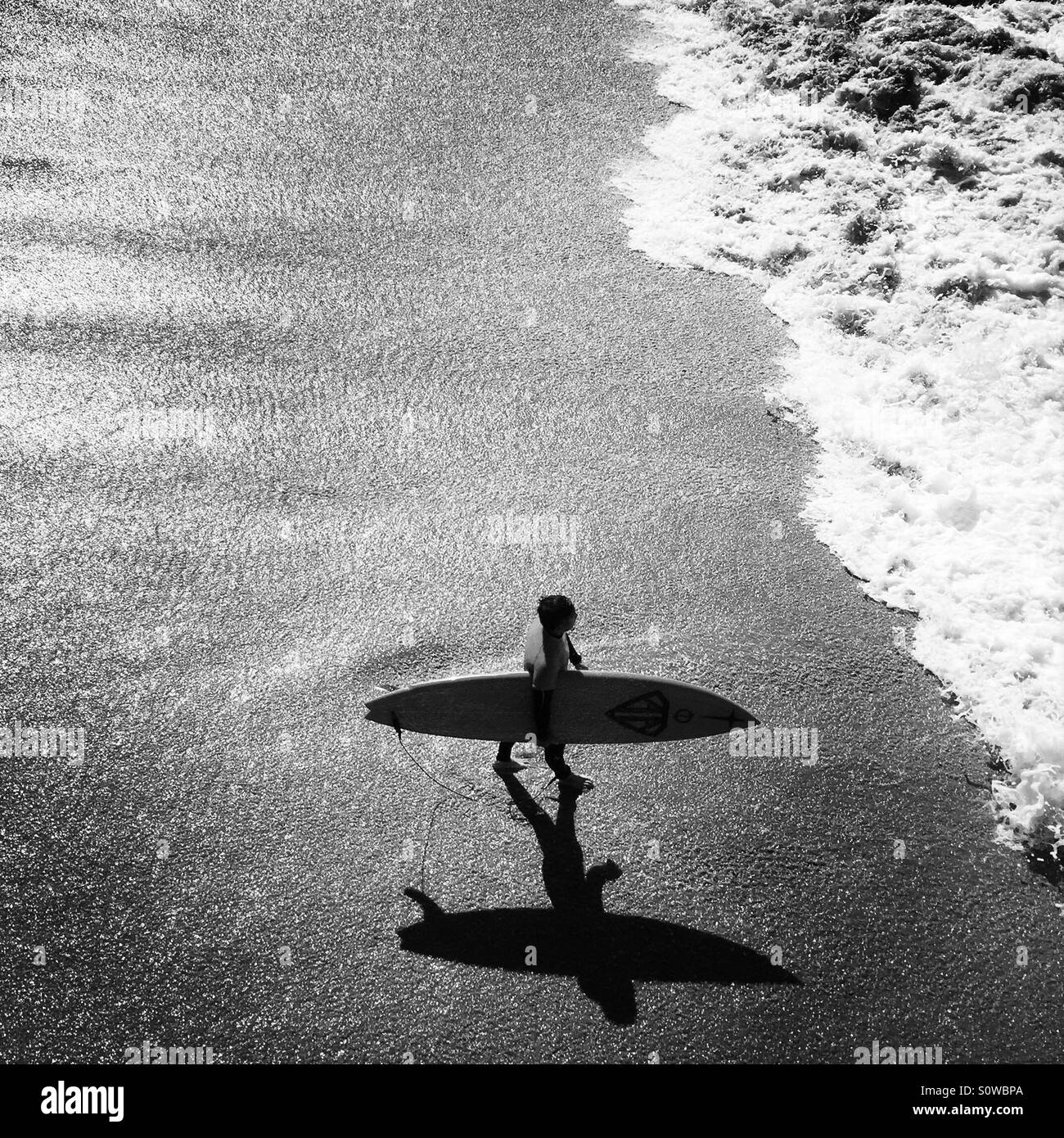 A male surfer walks into the surf. Manhattan Beach, California USA. - Smartphone Captured Stock Image