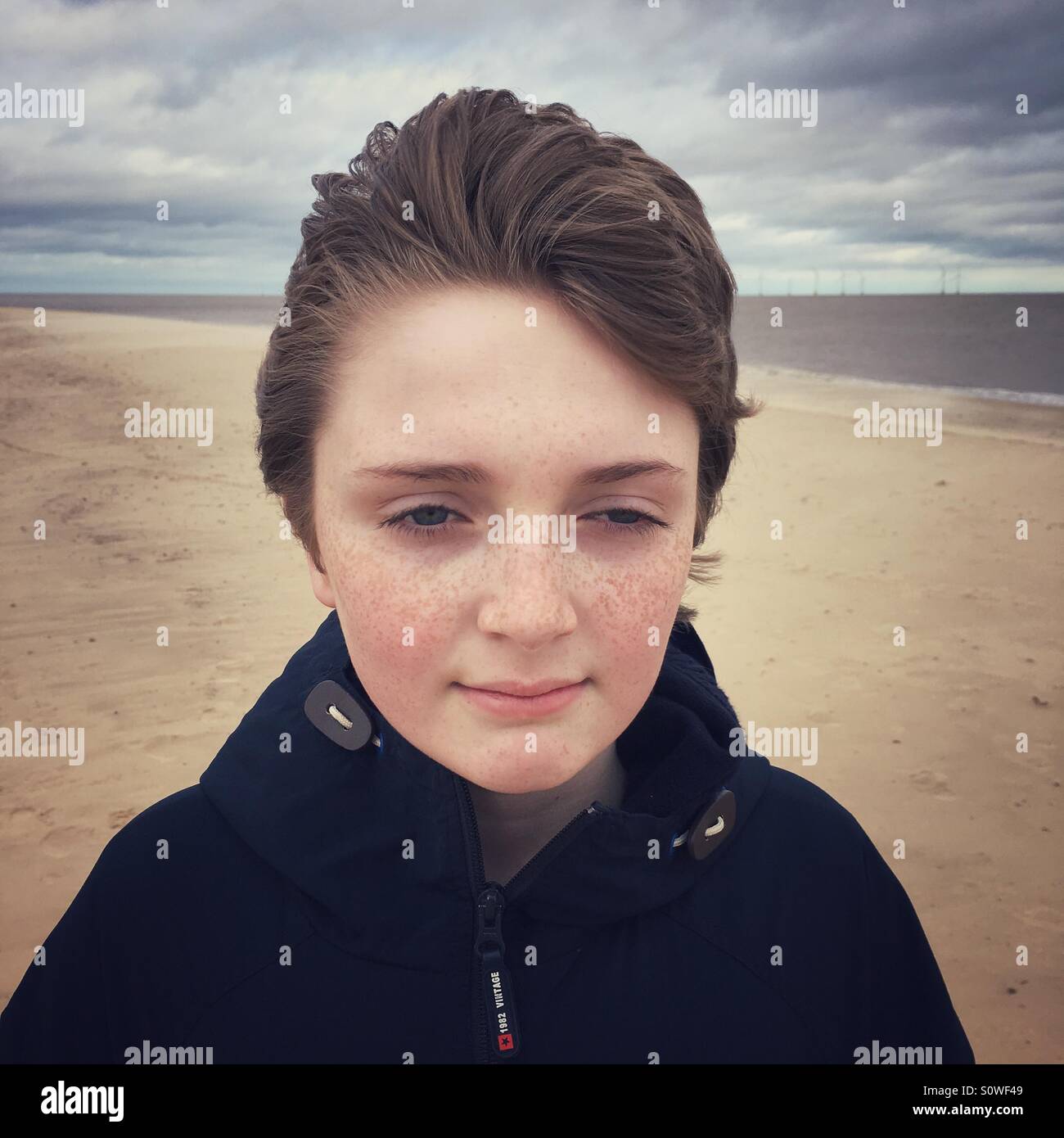 A young man getting his hair blown on a windy day at the beach Stock Photo