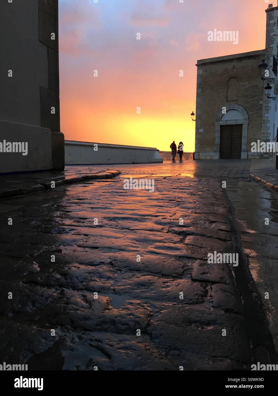 Couple strolling after rain in Sitges, Spain - Smartphone Captured Stock Image
