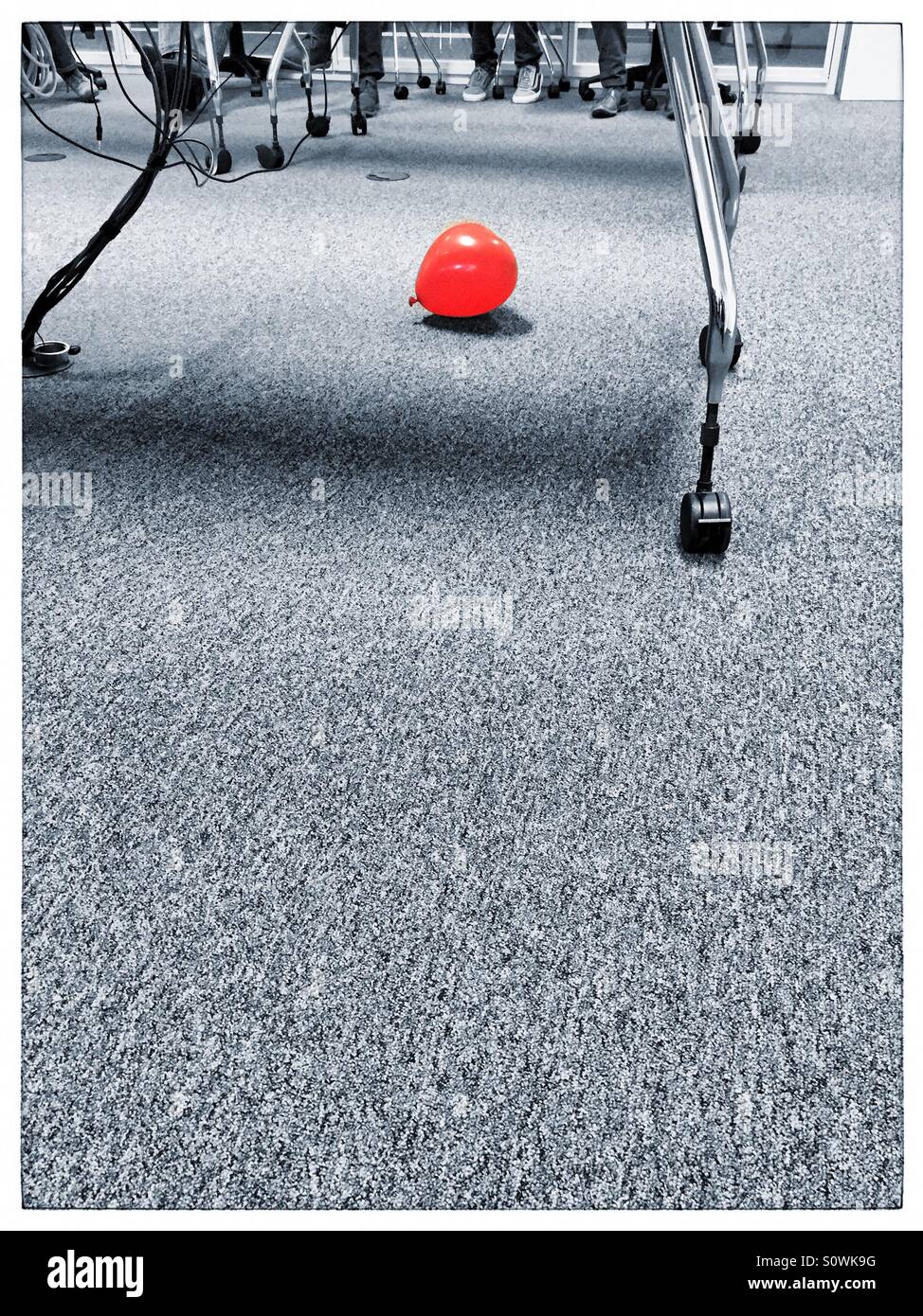 One red balloon in a room under a table - Smartphone Captured Stock Image