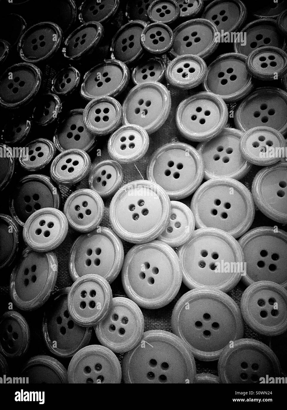 Black-and-white photo of round buttons with four thread holes - Smartphone Captured Stock Image