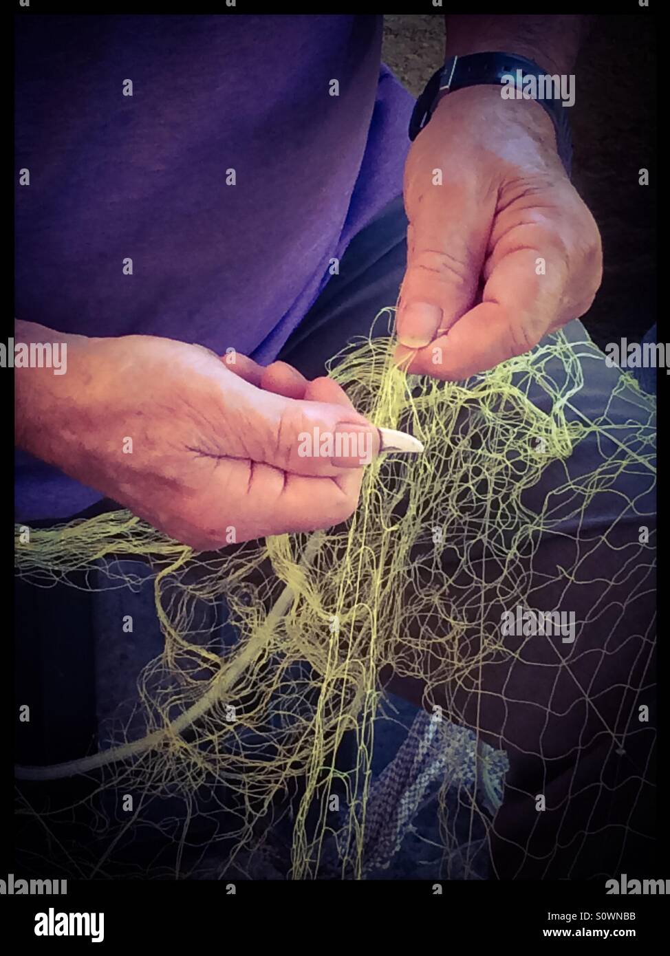 Fisherman mending fishing nets. Stock Photo