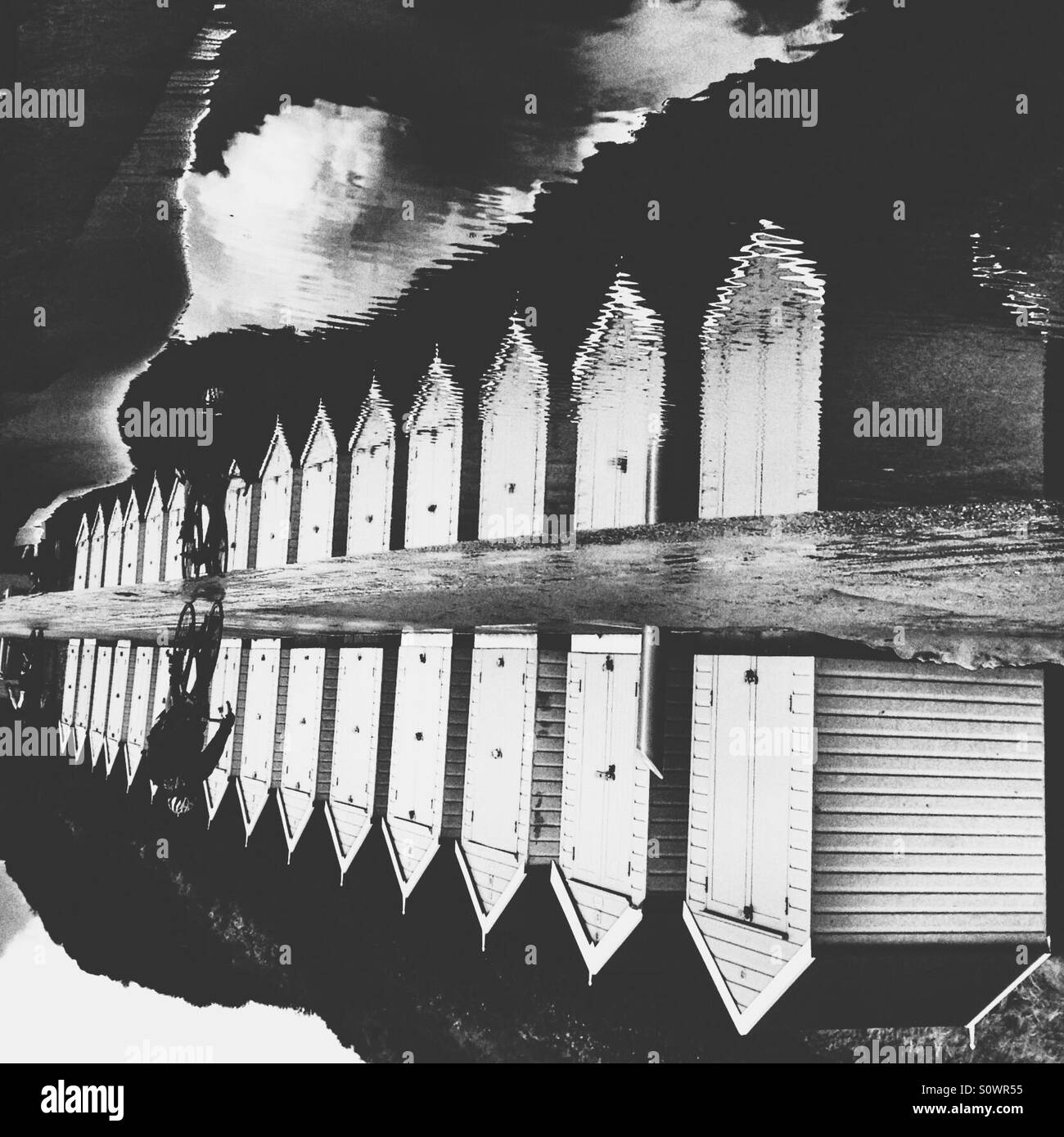 Puddle reflection of beach huts and a cyclist - Smartphone Captured Stock Image