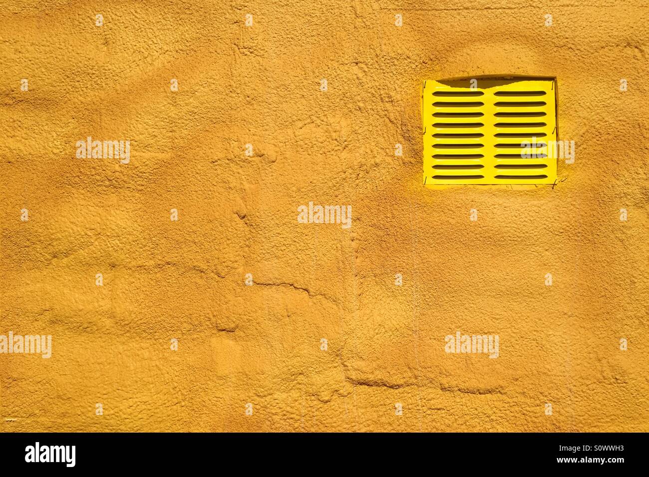 Yellow vent on a brick wall Stock Photo