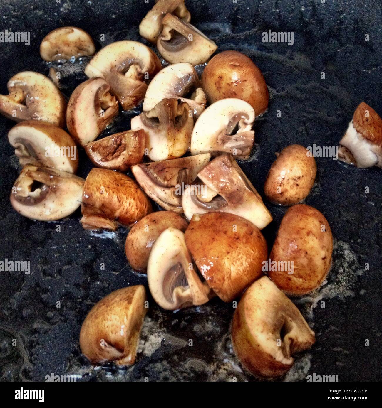 Mini Portobello Mushrooms Cut In Quarters Sauté In A Pan With Butter And Oil Stock Photo