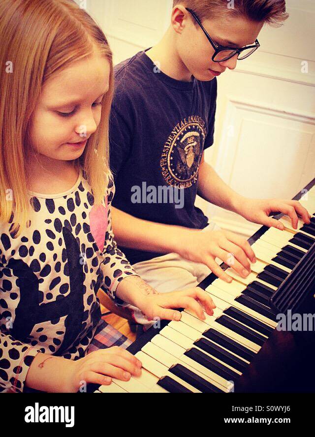 Siblings playing piano together in their pj's in the morning Stock Photo