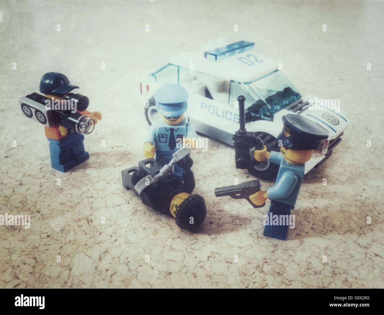 A scene of Lego policemen arresting a criminal while being filmed, an enactment of the TV show Cops - Smartphone Captured Stock Image