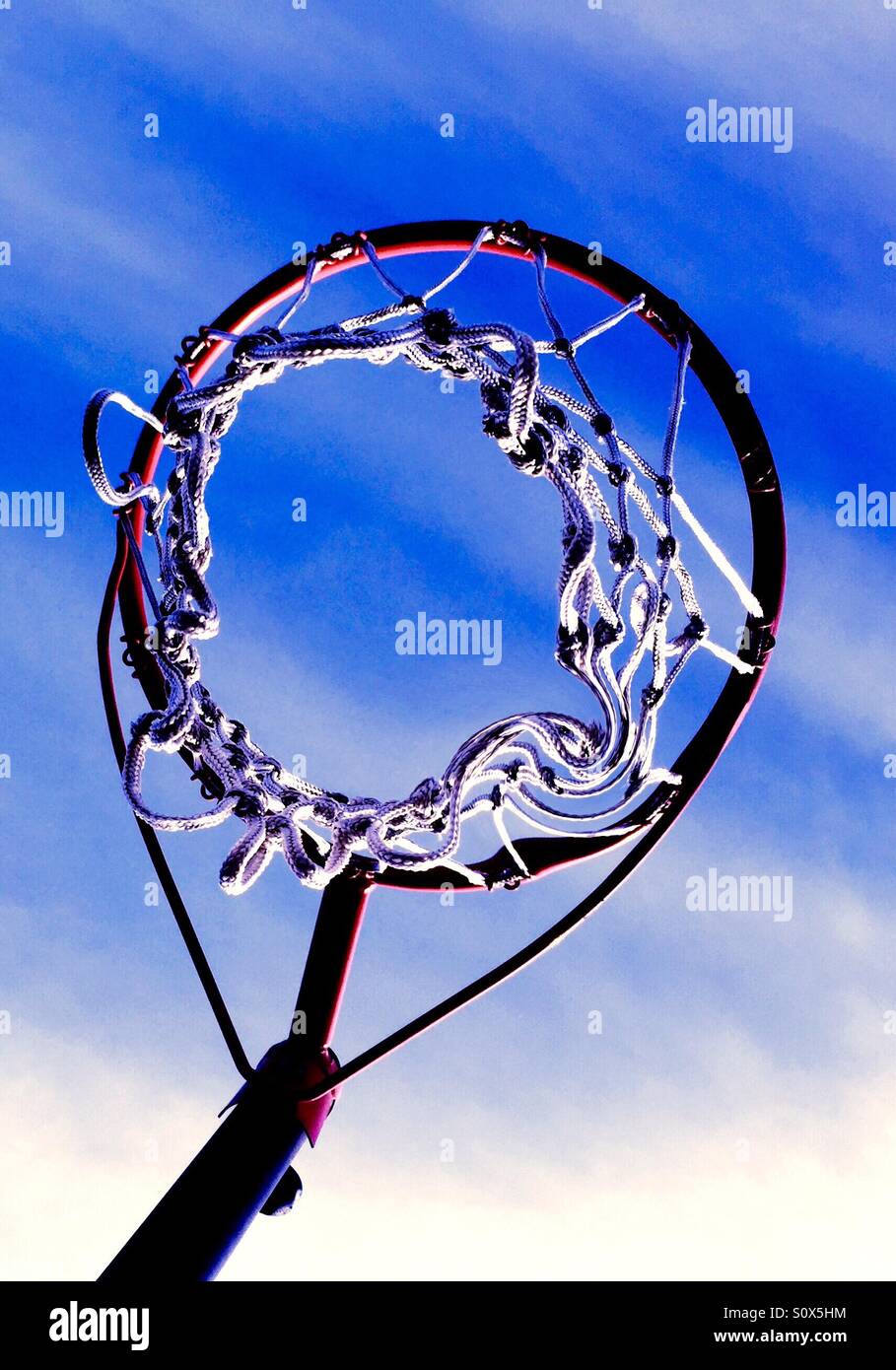 Looking up at a basketball net towards a blue sky. Stock Photo